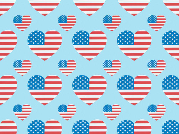 nahtloses Hintergrundmuster mit papiergeschnittenen Herzen aus amerikanischen Flaggen auf blau  - Foto, Bild