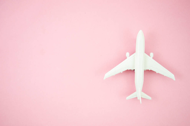 Top View model vlak, vliegtuig speelgoed op roze pastel achtergrond. Platte lay met Kopieer ruimte voor reis banner - Foto, afbeelding