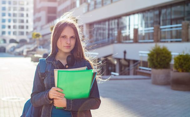 Back to school student teenager girl holding books and note books wearing backpack. Outdoor portrait of young teenager brunette girl with long hair. girl on city - 写真・画像
