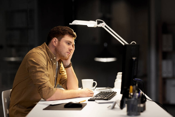 tired or bored man working late at night office - Фото, зображення