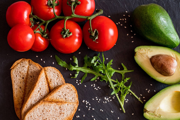 Tomates e abacate na mesa preta de perto, comida saudável colorida
  - Foto, Imagem