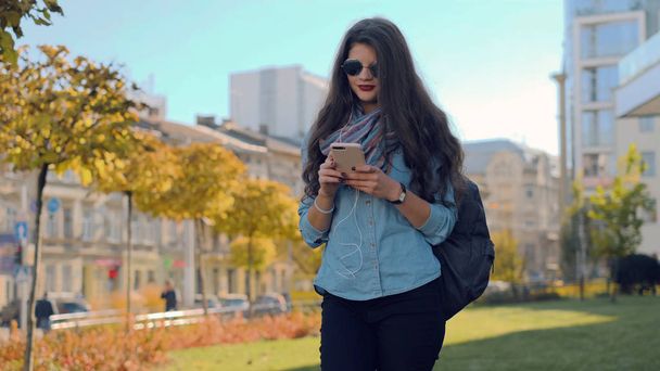 Retrato de una chica hermosa usando su teléfono inteligente caminando por la calle
 - Foto, imagen