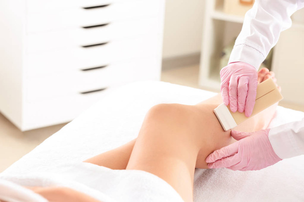 Beautician epilating legs of young woman in salon - Фото, зображення