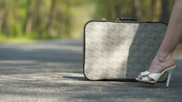 道路上のレトロなスーツケースの近くにハイヒールの靴の女性の4k.. - 映像、動画