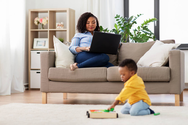 mãe usando laptop e bebê jogando blocos de brinquedo
 - Foto, Imagem