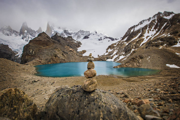 Stone pyramid in front of turquoise water lake in Patagonia, Los Glaciers National park. Beautiful view of Laguna De Los Tres, Monte Fitz Roy, Torre y Poincenot, El Chalten, Patagonia, Argentina - Photo, Image