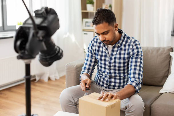 male video blogger opening parcel box at home - Fotó, kép