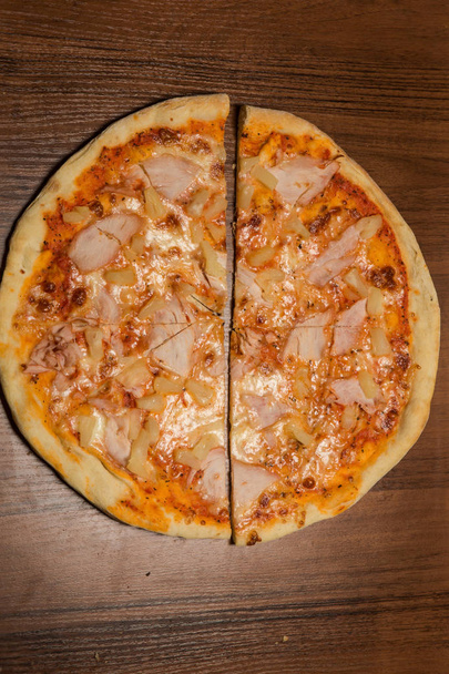 vue verticale sur deux moitiés de pizza au jambon et à l'ananas
 - Photo, image
