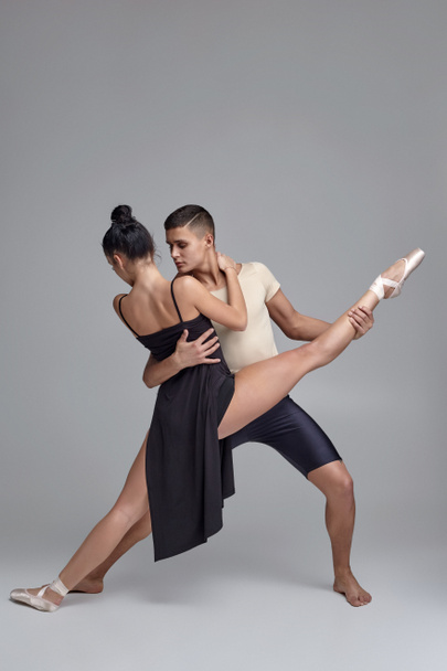 Двое современных артистов балета позируют на фоне серой студии
. - Фото, изображение