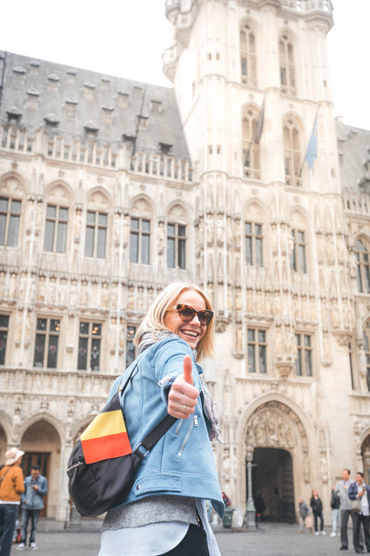 Young happy cheerful woman showing thumb up against the backdrop of the Grand Place in Brussels, Belgium - Foto, immagini