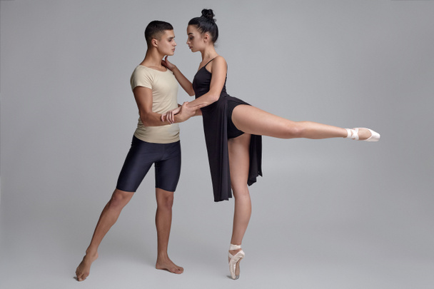 Two athletic modern ballet dancers are posing against a gray studio background. - Foto, Imagem