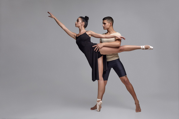 Két sportos modern balett-táncosok jelentenek ellen egy szürke stúdió háttér. - Fotó, kép