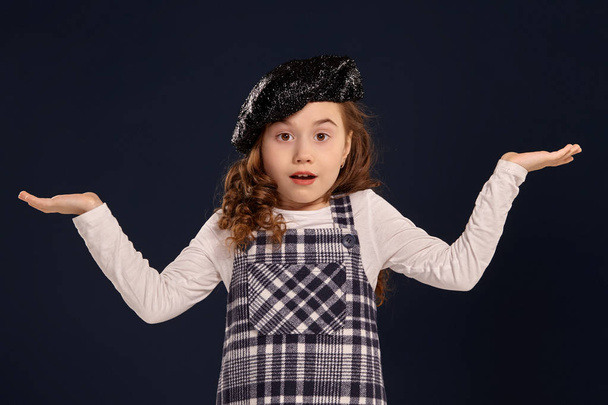 Stylish brunette kid is posing in studio on a black background. Childrens fashion. - Photo, Image