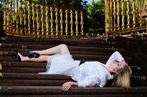 Блондинка сидить на сходах старих гранітних сходів. Молода жінка сучасний портрет
. - Фото, зображення