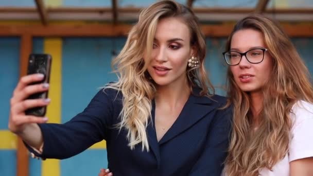 Twee aantrekkelijke vrouwen nemen selfie op telefoon en poseren - Video