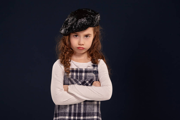 Stylish brunette kid is posing in studio on a black background. Childrens fashion. - Foto, afbeelding