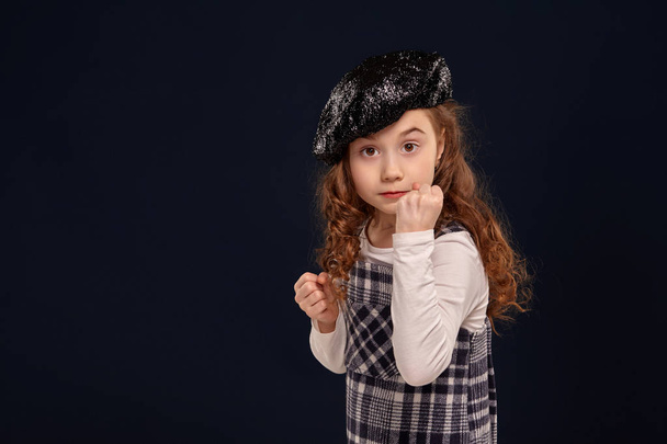 Stylish brunette kid is posing in studio on a black background. Childrens fashion. - Photo, image