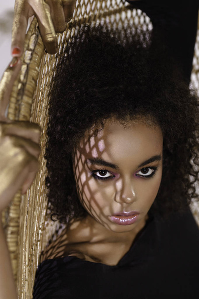 Modestudio Porträt einer schönen Frau in schwarzem Umhang mit Afro-Locken-Frisur. Mode und Schönheit - Foto, Bild