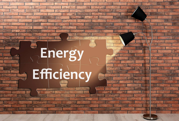 Stylish lamp on floor near brick wall. Energy efficiency concept - Foto, imagen