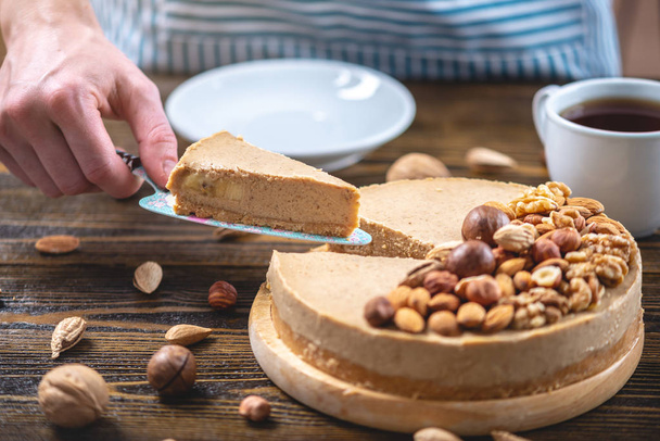 Piece of raw nutty cake on a blue wooden background. Healthy fresh summer vegan dessert. Gluten free and sugar free food - Foto, afbeelding