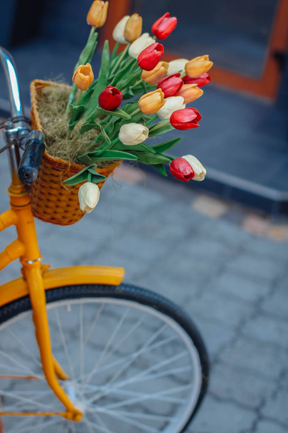Φωτεινό πορτοκαλί ποδήλατο με καλάθι λουλουδιών - Φωτογραφία, εικόνα