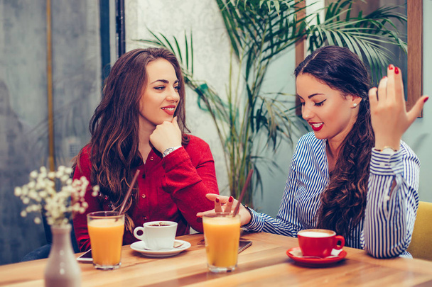 Deux belles jeunes femmes assises dans un café, buvant du café et
 - Photo, image