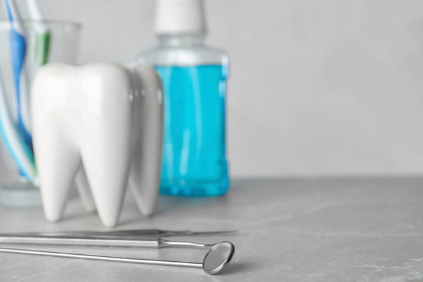 Dentist tools and tooth shaped holder on table. Space for text - 写真・画像