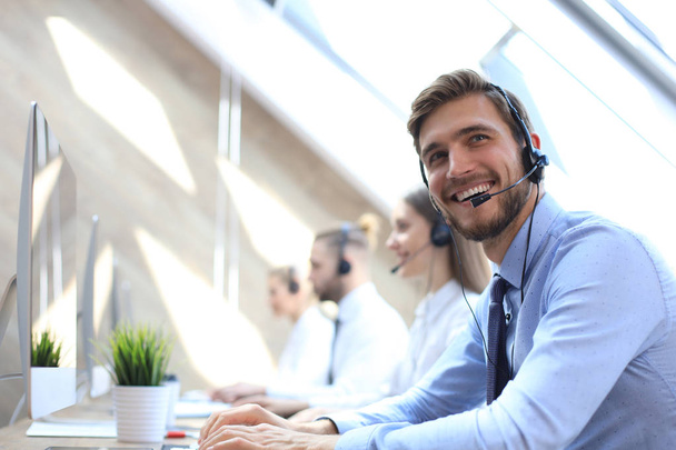 Portrait of call center worker accompanied by his team. Smiling customer support operator at work. - Fotoğraf, Görsel