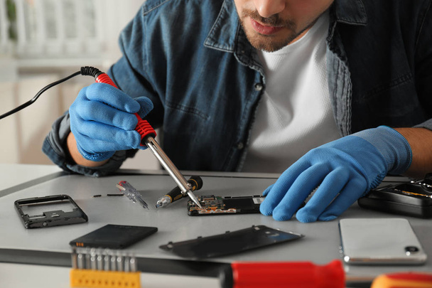 Technician repairing broken smartphone at table, closeup - Foto, Imagem