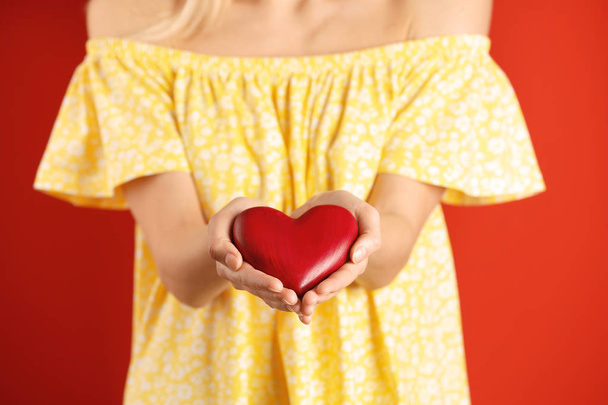 Woman with decorative heart on color background, closeup - Zdjęcie, obraz