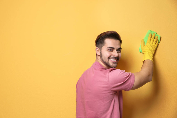 Man cleaning color wall with rag. Space for text - Foto, afbeelding