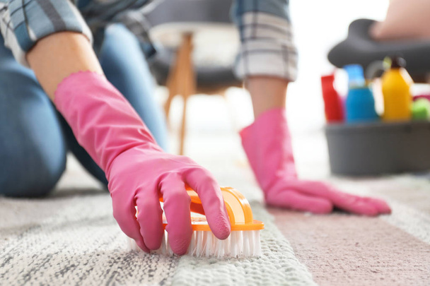 Woman cleaning carpet with brush in living room, closeup - Foto, afbeelding