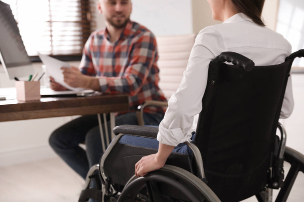 Woman in wheelchair with her colleague at workplace, closeup - Zdjęcie, obraz
