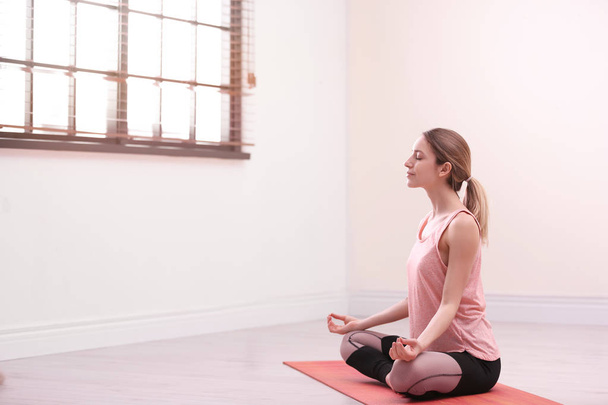 Genç bir kadın boş bir odada meditasyon yapıyor, mesaj için yer var. Zen kavramı - Fotoğraf, Görsel