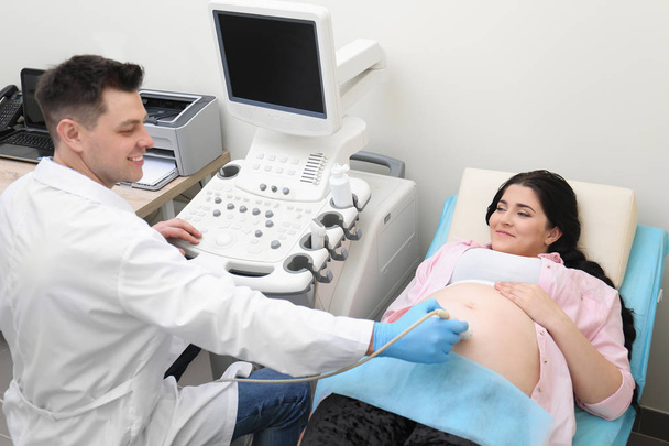 Young pregnant woman undergoing ultrasound scan in clinic - Φωτογραφία, εικόνα