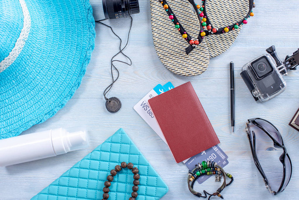 旅行の休日用品:帽子、サングラス、フリップフロップ、カメラ、青い背景にパスポート。トップビュー。フラットレイ - 写真・画像