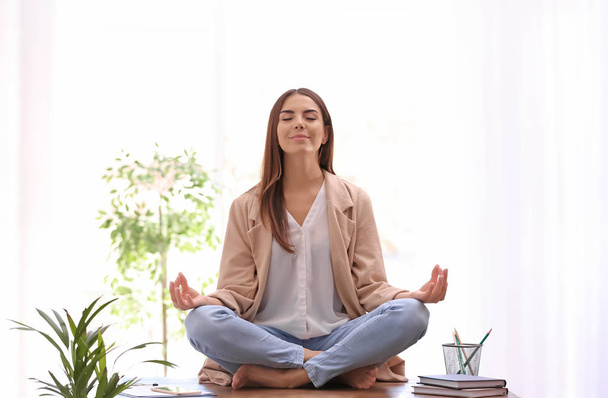 Young businesswoman meditating at workplace. Zen concept - Photo, image