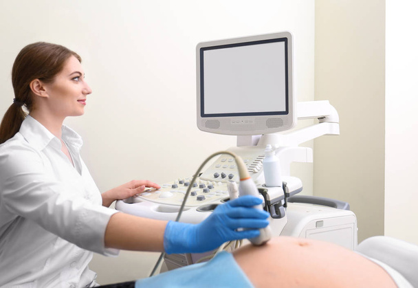 Young pregnant woman undergoing ultrasound scan in clinic - Foto, imagen