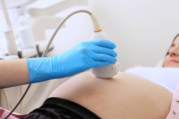Pregnant woman undergoing ultrasound scan in clinic, closeup - Fotoğraf, Görsel