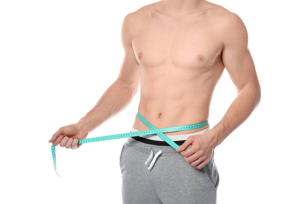Young man with measuring tape showing his slim body on white background, closeup - Fotografie, Obrázek