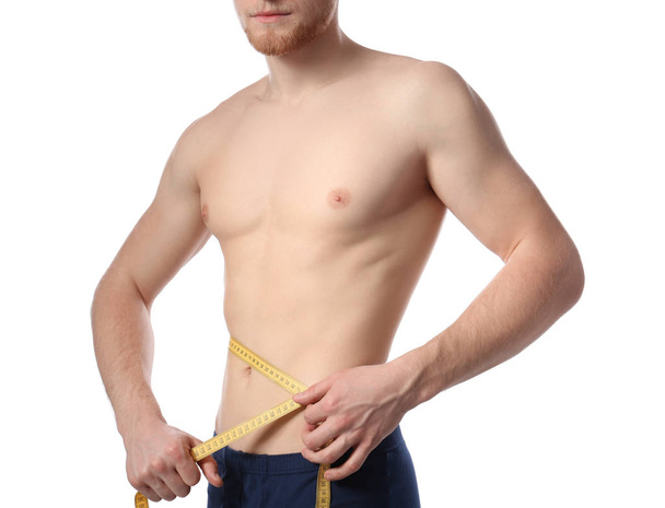 Young man with measuring tape showing his slim body on white background, closeup - Fotoğraf, Görsel