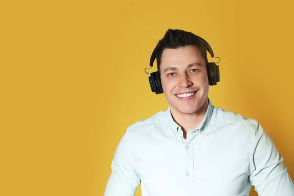 Man enjoying music in headphones on color background. Space for text - Zdjęcie, obraz