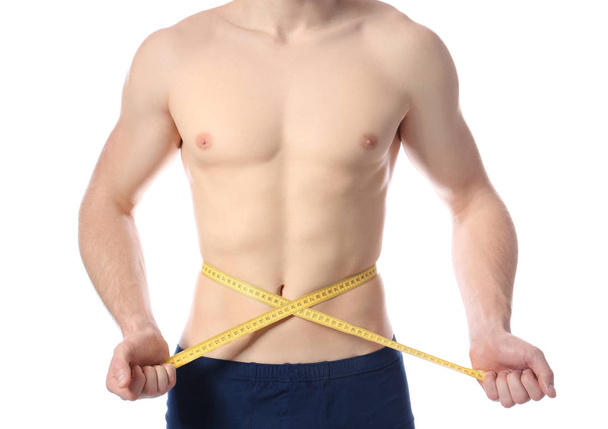 Young man with measuring tape showing his slim body on white background, closeup - Foto, imagen