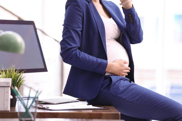 Young pregnant woman in suit at workplace, closeup - Photo, image