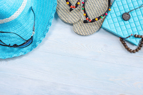 Туристические принадлежности для отдыха: шляпа, солнцезащитные очки, шлепанцы, паспорт камеры на синем фоне. Отправляясь в путешествие к морю
 - Фото, изображение