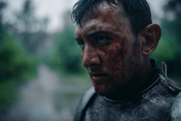 Yüzünde kan ve yaralar olan bir ortaçağ şövalyesi görüntüsünde genç adamın portresi. - Fotoğraf, Görsel