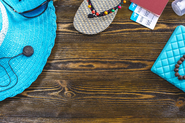 Туристические принадлежности: шляпа, солнцезащитные очки, шлепанцы, паспорт и авиабилеты на старом деревянном фоне. Вид сверху
 - Фото, изображение