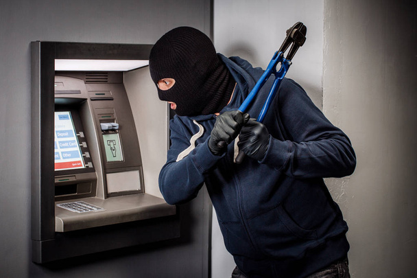 Thief with bolt cutter hacks an ATM. Law and crime concept - Fotó, kép