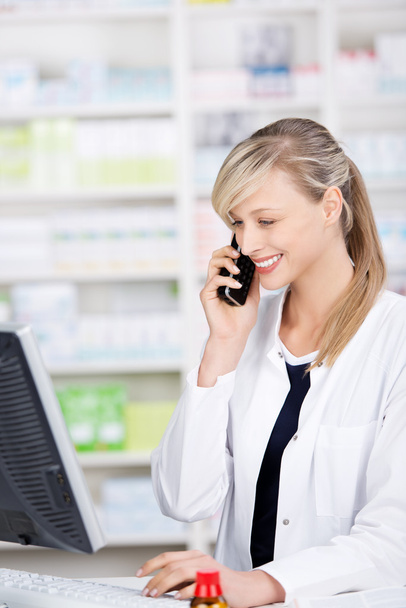 Smiling attractive pharmacist talking at the phone - Фото, изображение