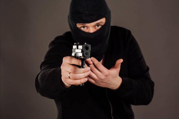 Burglar or robber aiming with pistol. man in black mask - Fotó, kép